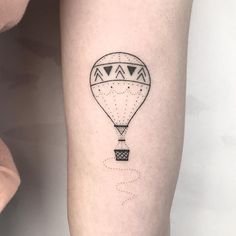 a small hot air balloon tattoo on the right inner arm and leg, with an arrow in the middle