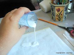 someone is pouring something into a cup on a table with scissors and other crafting supplies