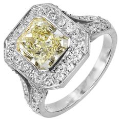 Handmade yellow diamond with diamond halo platinum engagement ring. The EGL certified 2.06ct center stone is a natural fancy yellow cushion cut diamond of rectangular shape with squared off corners. Top to bottom and side to side brilliance. Set in an 8 sided rectangular bead set top with round full cut diamonds in a split shank style setting with diamonds along each shoulder. 1 cut corner Radiant cut diamond 2.06cts, SI1, Fancy Light-light yellow diamond natural color. 8.10 x 6.80 x 4.21mm, 61. Yellow Diamond Platinum Ring With Center Stone, Yellow Diamond Ring With Radiant Cut And Diamond Accents, Yellow Diamond Ring With Radiant Cut And Accents, Yellow Radiant Cut Diamond Ring With Accents, Yellow Platinum Diamond Ring With Diamond Cut, Yellow Diamond Cut Platinum Ring, Yellow Radiant Cut Diamond Ring With Center Stone, Yellow Diamond Ring With Cushion Cut, Yellow Emerald Cut Diamond Ring With Halo Setting