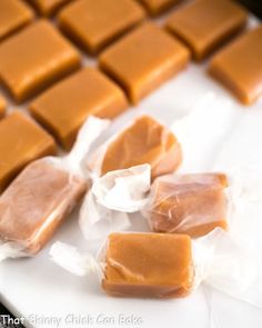 pieces of caramel candy sitting on top of a white plate with plastic wrappers