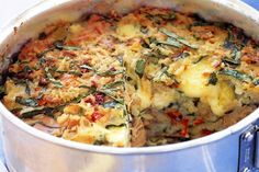 a casserole dish with spinach, cheese and other toppings in a metal pan