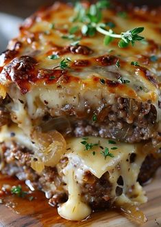 a cheesy lasagna with onions and cheese on a wooden cutting board