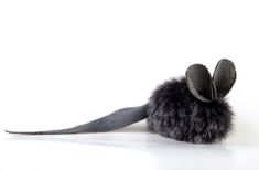 a stuffed animal mouse with black fur on it's back legs and ears, sitting in front of a white background