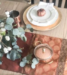 the table is set with plates, silverware and flowers on it's placemats