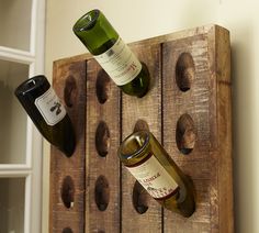 two bottles of wine are sitting on a wooden rack with holes in the wall to hold them