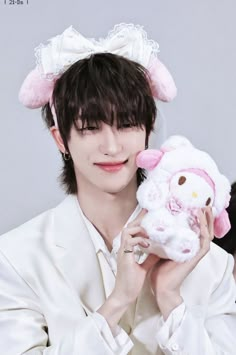 a woman holding a stuffed animal in her hands and wearing a white suit with pink ears