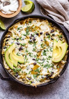 an enchilada dish with black beans, avocado and sour cream