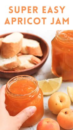 a hand holding a jar of apricot jam next to sliced peaches and lemons