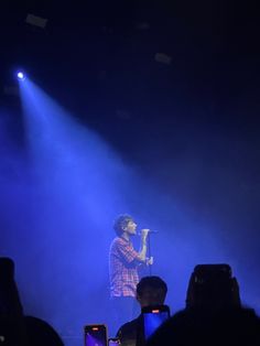 a man standing on top of a stage holding a microphone in front of a crowd