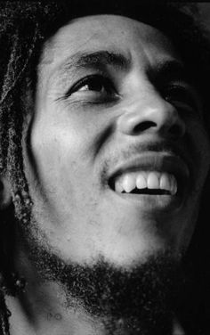 a black and white photo of a man with dreadlocks