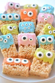 rice krispy treats decorated like monsters and eyes are on a white plate with other food items in the background