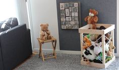 two teddy bears sitting on chairs in a living room next to a wall with letters