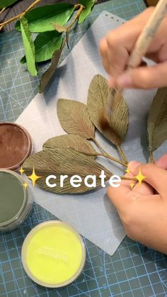 two hands are painting leaves with yellow and green paint