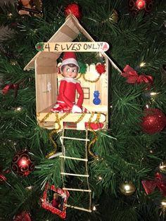 an elf is sitting on top of a house ornament in the christmas tree