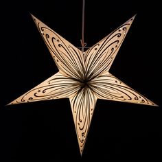 a paper star ornament hanging from a string on a black background in the shape of a flower