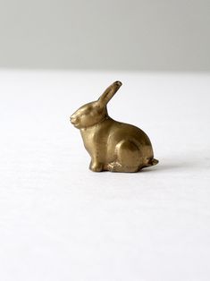 a gold rabbit figurine sitting on top of a white surface