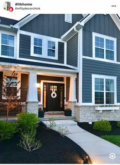 the front entrance of a house with landscaping and lights on it's side walk