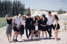 a group of young people standing next to each other on the side of a road