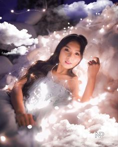 a woman sitting in the clouds surrounded by lights