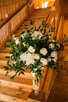 a vase filled with white flowers sitting on top of a wooden staircase