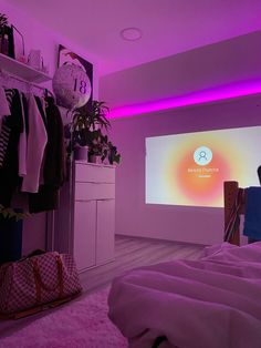 a bedroom with purple lighting and clothes hanging on the rack in front of a projector screen