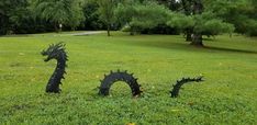 two black dragon sculptures sitting on top of a lush green field