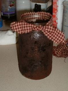 a brown jar with a red and white checkered ribbon on it sitting on a counter