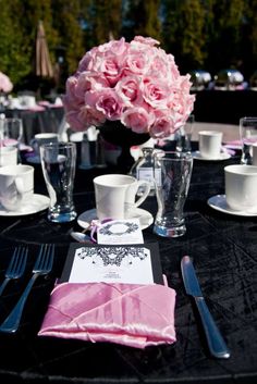 the table is set with pink flowers and silverware