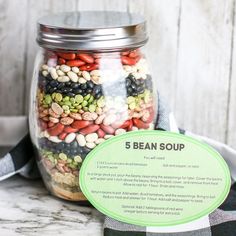 a glass jar filled with beans and other things on top of a table next to a sign