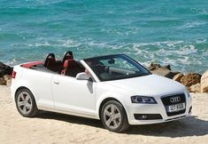 a white convertible car parked on the beach