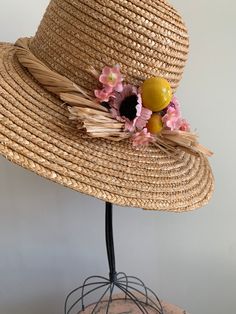 "This is a vintage 1950's straw sun hat. The hat is intricately woven with a braided section across the brim. There is also pink tone faux floral details. By the faux flowers there are also plastic faux fruit adding a pop of color and texture. The hat is in excellent condition. Measurements: Circumference: 21\" | Inside Depth: 5.5\" | Brim Depth: 4\" | Brim Circumference: 46\" Unless otherwise stated all vintage items are used and may have minor to moderate wear or discoloration considering the Vintage Sun Hat, Pink Straw Hat For Summer, Vintage Handmade Straw Hat With Short Brim, Beige Straw Hat For Garden Party, Vintage Handmade Adjustable Straw Hat, Handmade Vintage Straw Hat With Adjustable Fit, Handmade Vintage Wide Brim Straw Hat, Vintage Adjustable Handmade Straw Hat, Handmade Adjustable Vintage Straw Hat