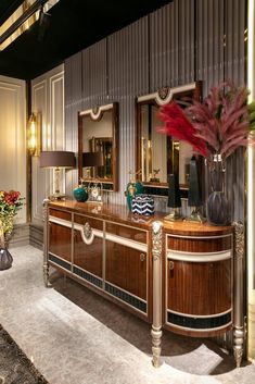 a large wooden dresser sitting inside of a living room next to a vase filled with flowers