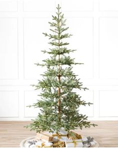 a small christmas tree sitting on top of a white plate with presents under the tree