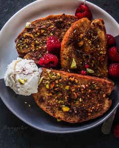 two pieces of french toast on a plate with ice cream and raspberries