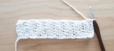 a crocheted piece of white yarn next to a pair of scissors on a wooden surface