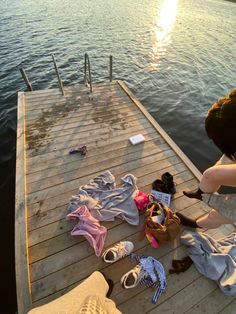 a person sitting on a dock next to some clothes