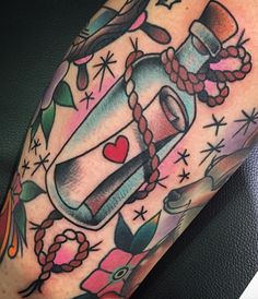 a bottle with a heart inside is sitting on the arm, surrounded by other tattoos