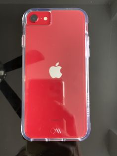 an iphone case sitting on top of a table next to a black phone with a red apple logo