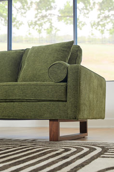 a green couch sitting in front of a window