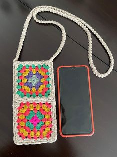 a cell phone is laying next to a crocheted bag on a table with a tag