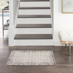 a white staircase leading up to a living room with a rug on the floor in front of it