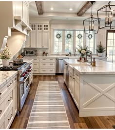 a large kitchen with white cabinets and wood flooring, along with an island in the middle