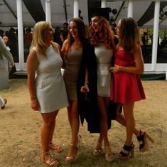 three beautiful women standing next to each other in front of a tent at a party