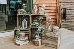 an assortment of wooden crates with flowers and candles in them sitting on the floor next to a building