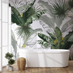 a bath tub sitting next to a window covered in green leafy wallpaper on a wooden floor