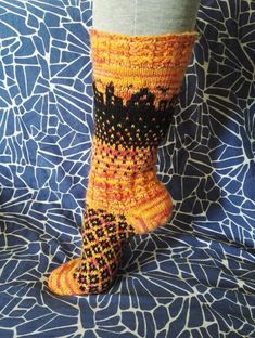 the legs of a person wearing knitted socks with black and orange designs on them