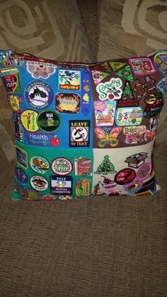 a colorful pillow with many stickers on it sitting on a couch next to a chair