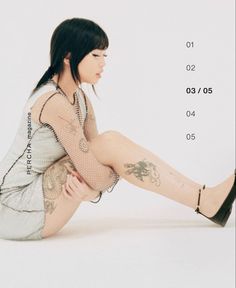 a woman is sitting on the floor with her legs crossed and tattoos on her body