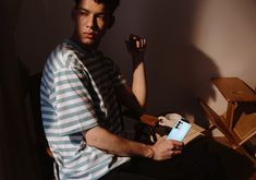 a young man sitting in a chair with his hand on his hip while reading a book