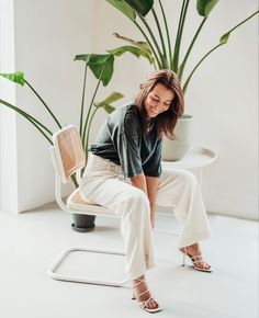 a woman sitting on top of a chair next to a potted plant